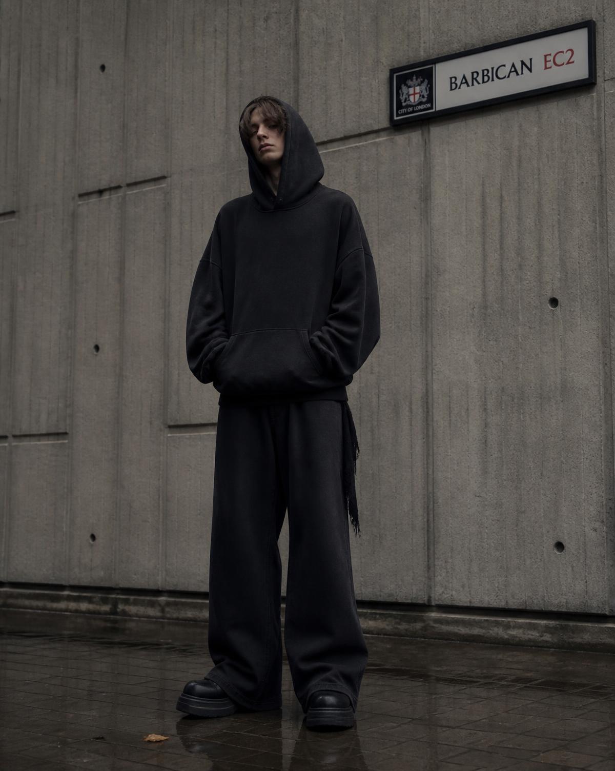 Man wearing the STRIVE heavyweight hoodie against a concrete wall