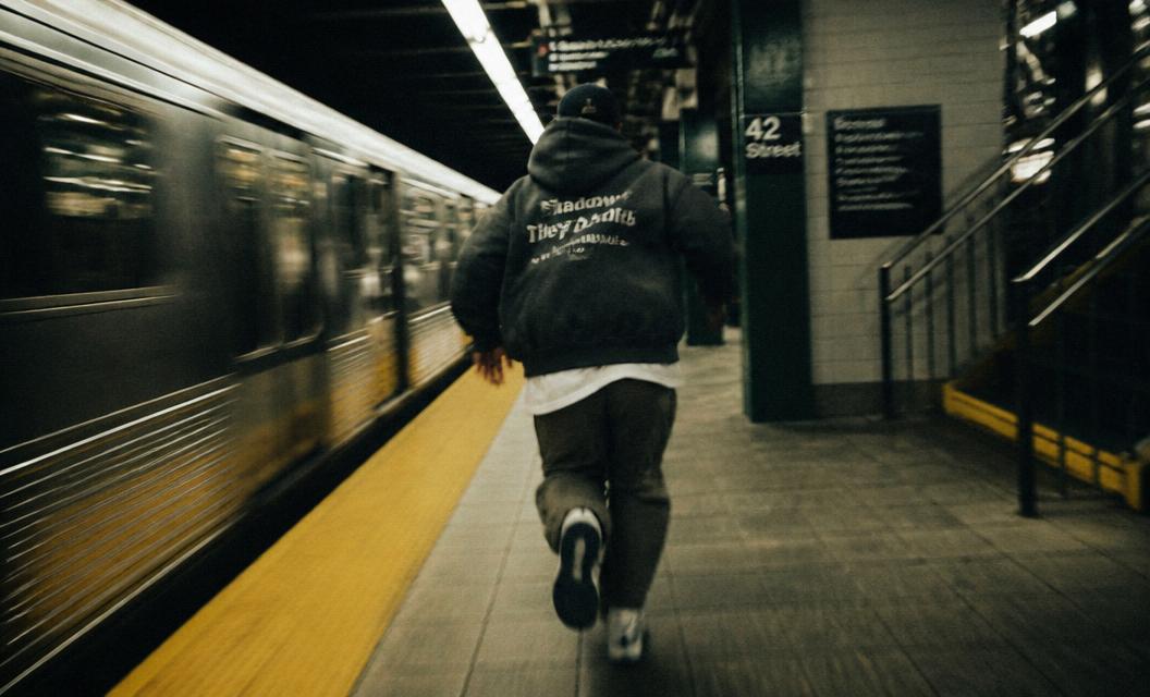 Man in a STRIVE hoodie running through a subway station